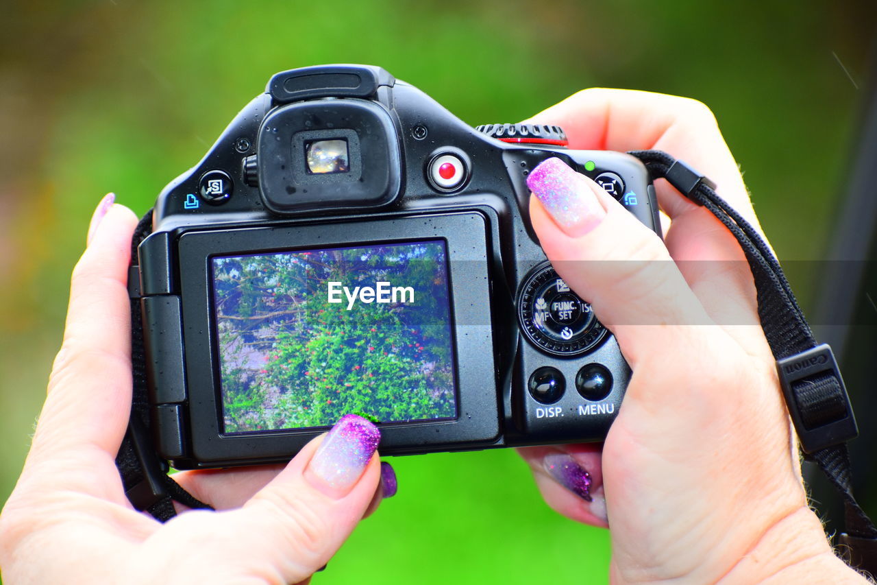 Cropped hands of woman holding digital camera