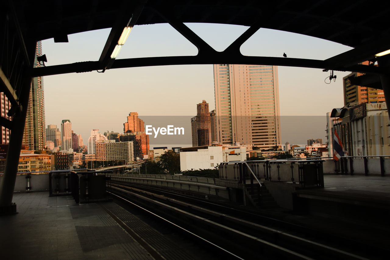 Railroad tracks by buildings in city against sky