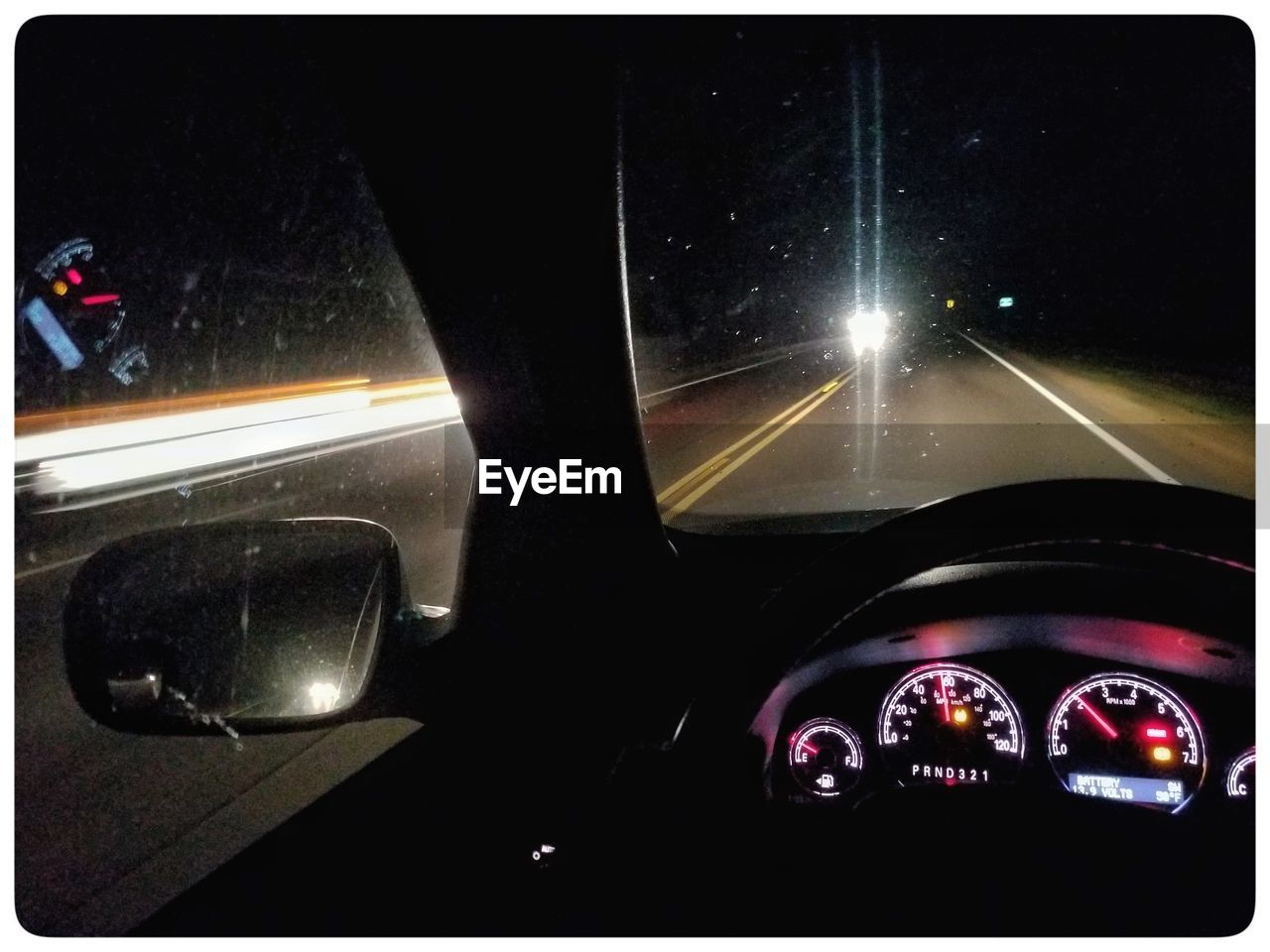 CLOSE-UP OF CAR WINDSHIELD AT ILLUMINATED BUS