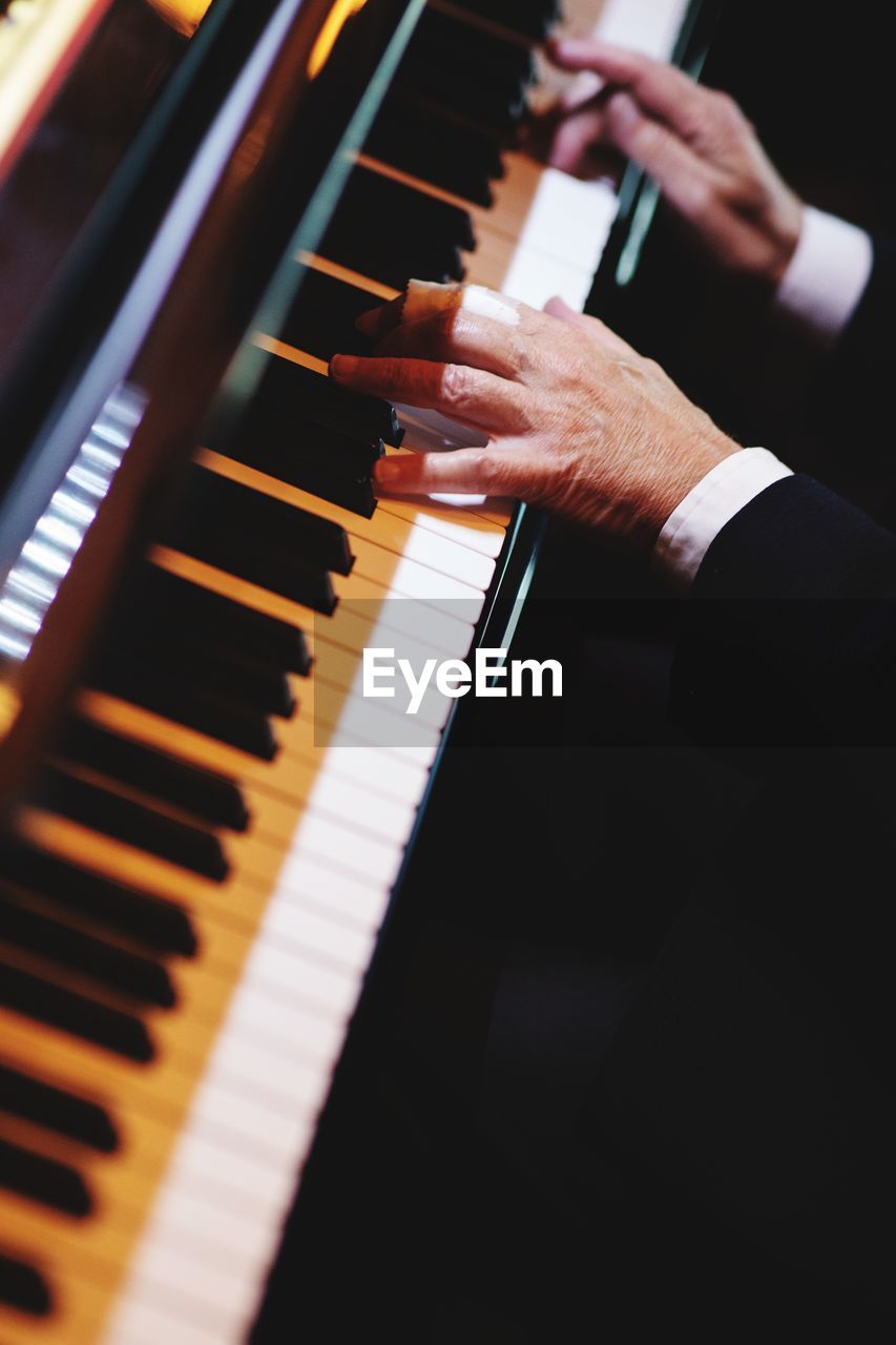 Cropped hands of man playing piano