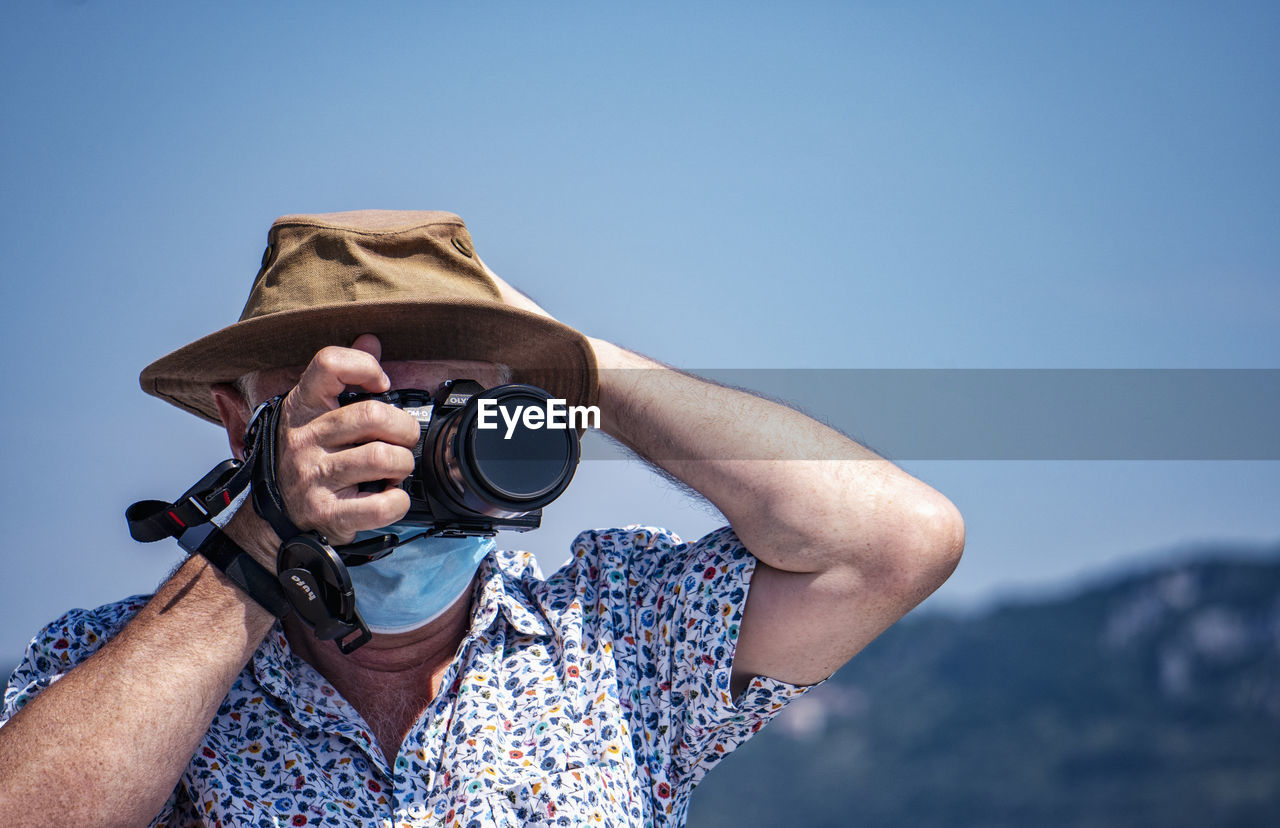 blue, one person, adult, sky, binoculars, men, activity, nature, technology, portrait, holding, copy space, hat, person, camera, spring, leisure activity, clear sky, clothing, sun hat, day, headshot, looking through an object, fashion accessory, mountain, vacation, casual clothing, outdoors, travel, adventure, trip, front view, exploration, occupation, cowboy hat, looking, tourist, lifestyles, summer, tourism, glasses