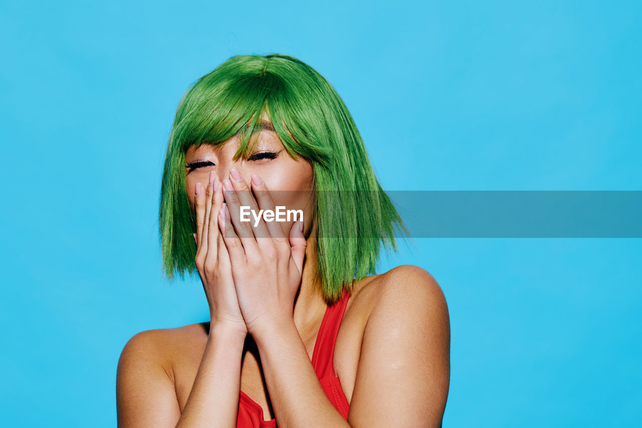 close-up of young woman with eyes closed against blue background