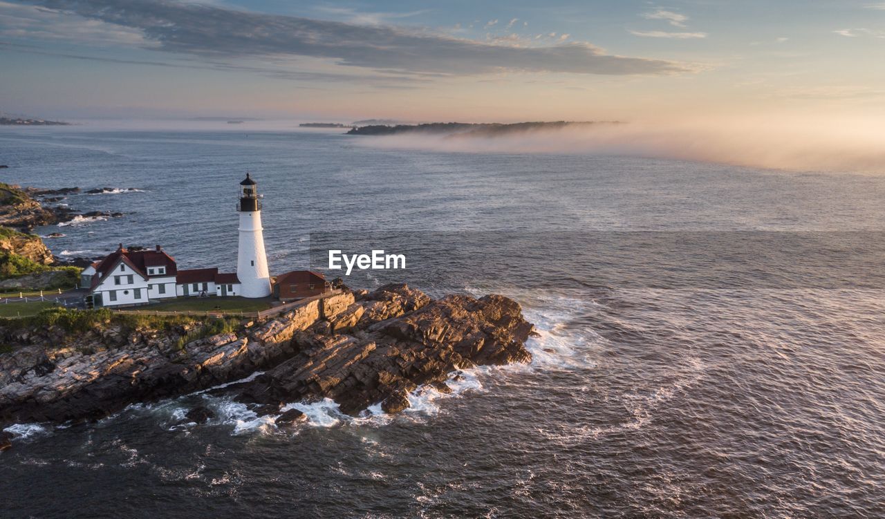 High angle view of lighthouse by sea against sky during sunset