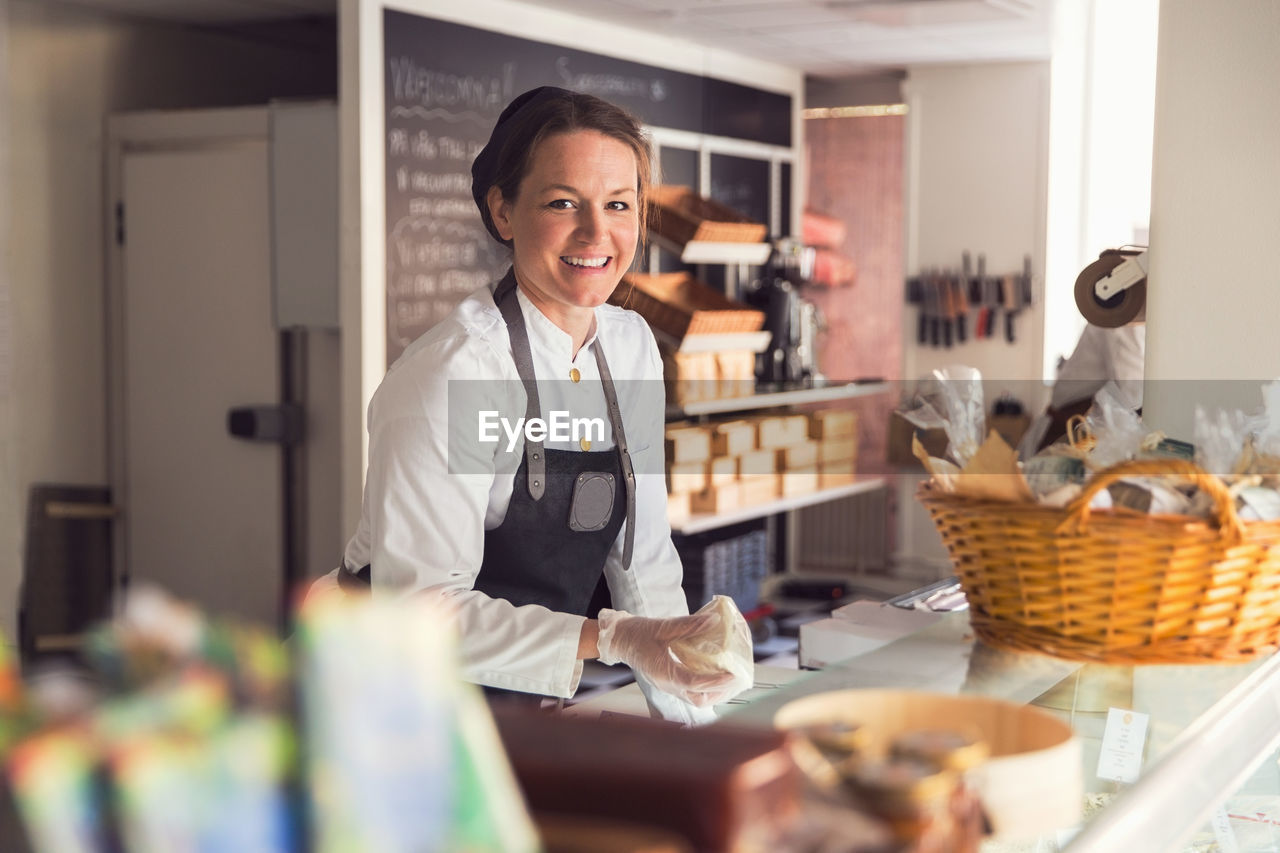 Portrait of happy female owner working at display cabinet in grocery store