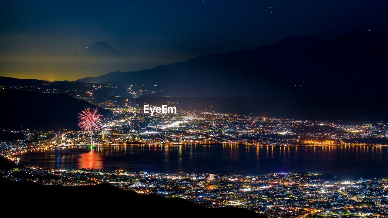 Illuminated cityscape against sky at night