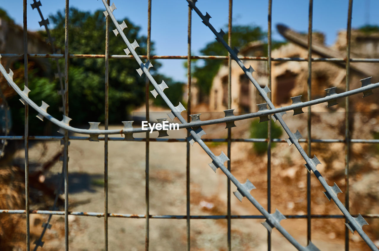 CLOSE-UP OF CHAINLINK FENCE AGAINST BLURRED BACKGROUND