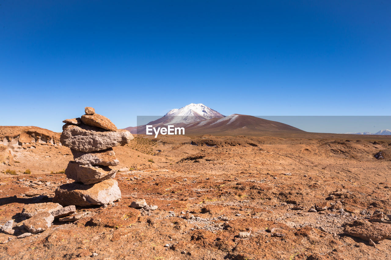 Scenic view of arid landscape against clear blue sky