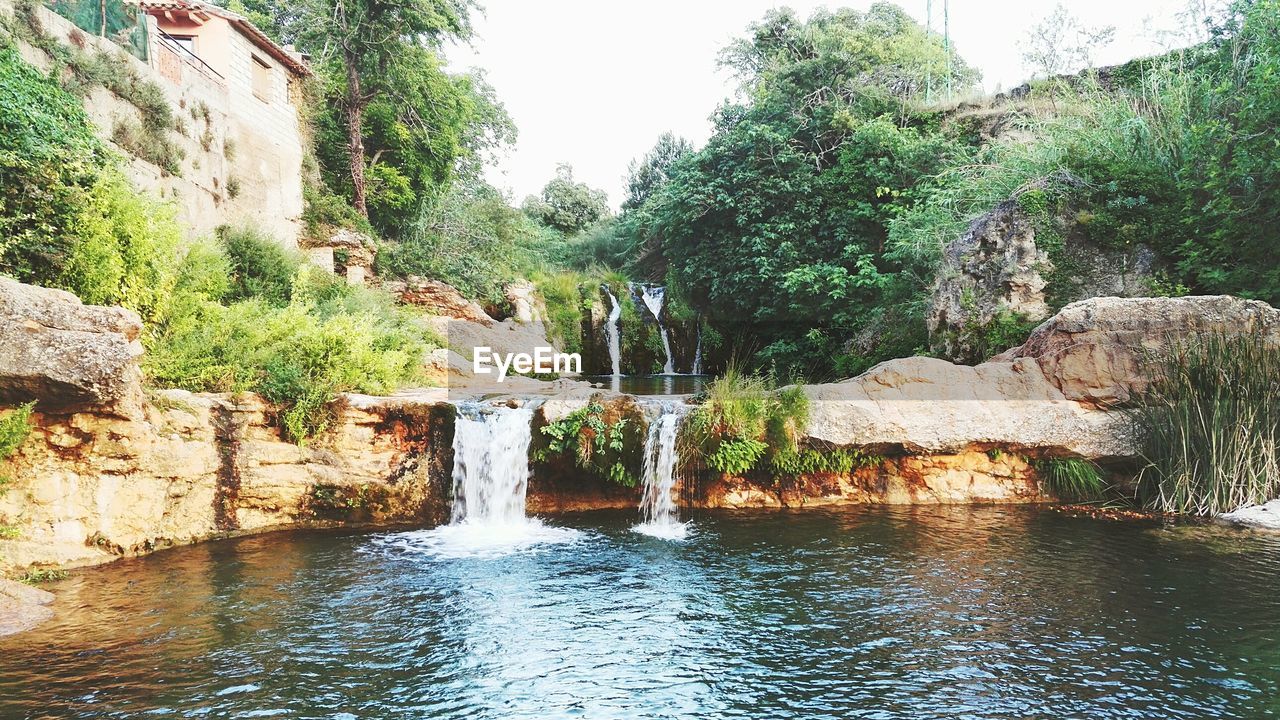 SCENIC VIEW OF WATERFALL AGAINST SKY