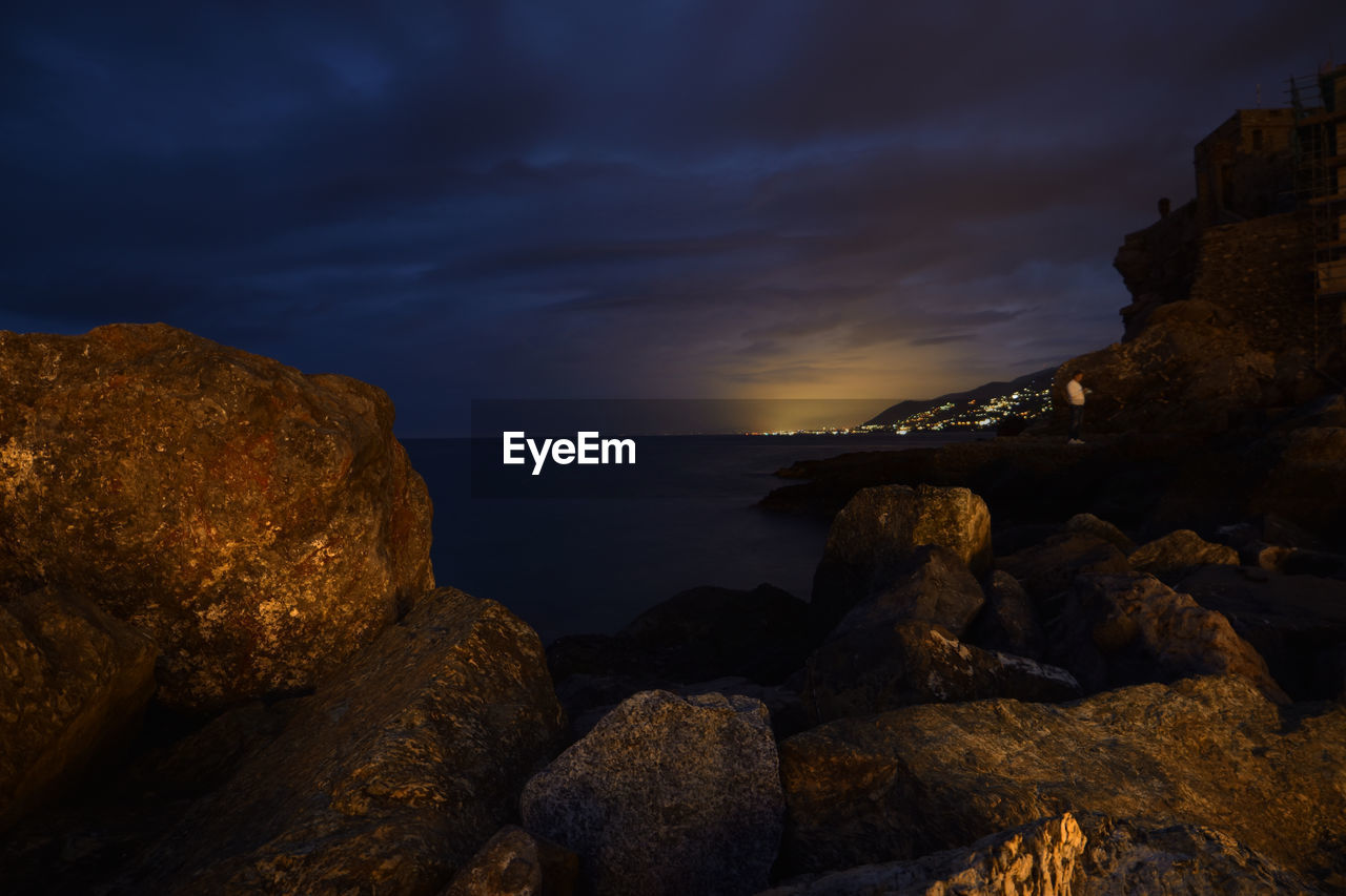 ROCKS ON BEACH AGAINST SKY AT SUNSET