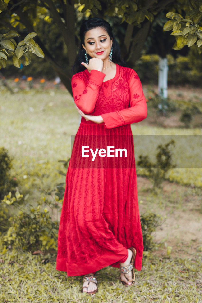 Portrait of young woman standing against plants