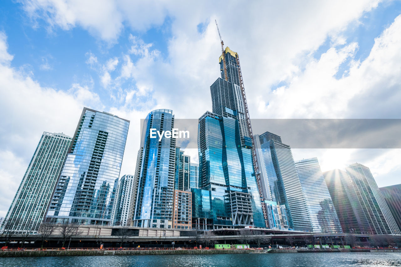 Low angle view of modern buildings against cloudy sky