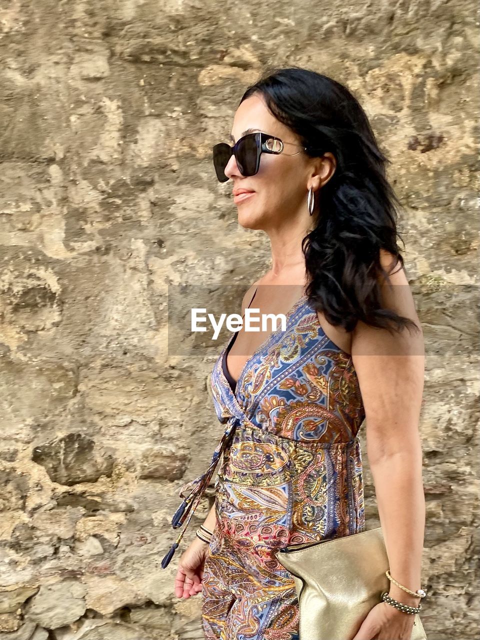 Young woman wearing sunglasses standing against wall