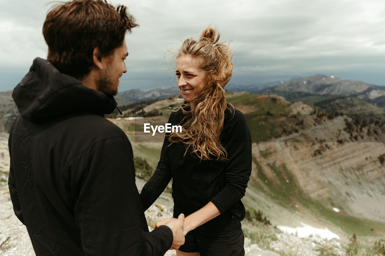 Woman awkward but happy, smiles during a surprise mountain engagement