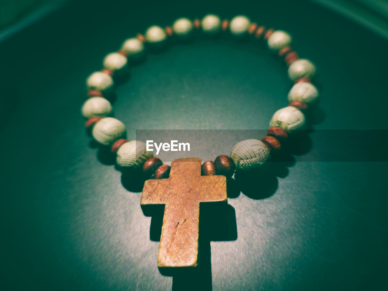 Close-up of wooden cross on bracelet over table