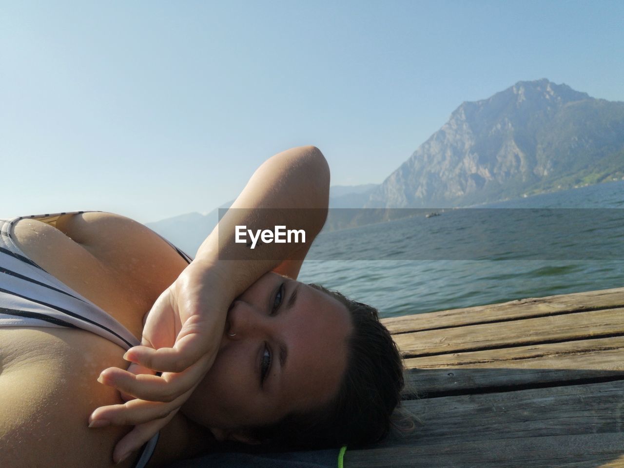 Portrait of young woman relaxing by sea on jetty