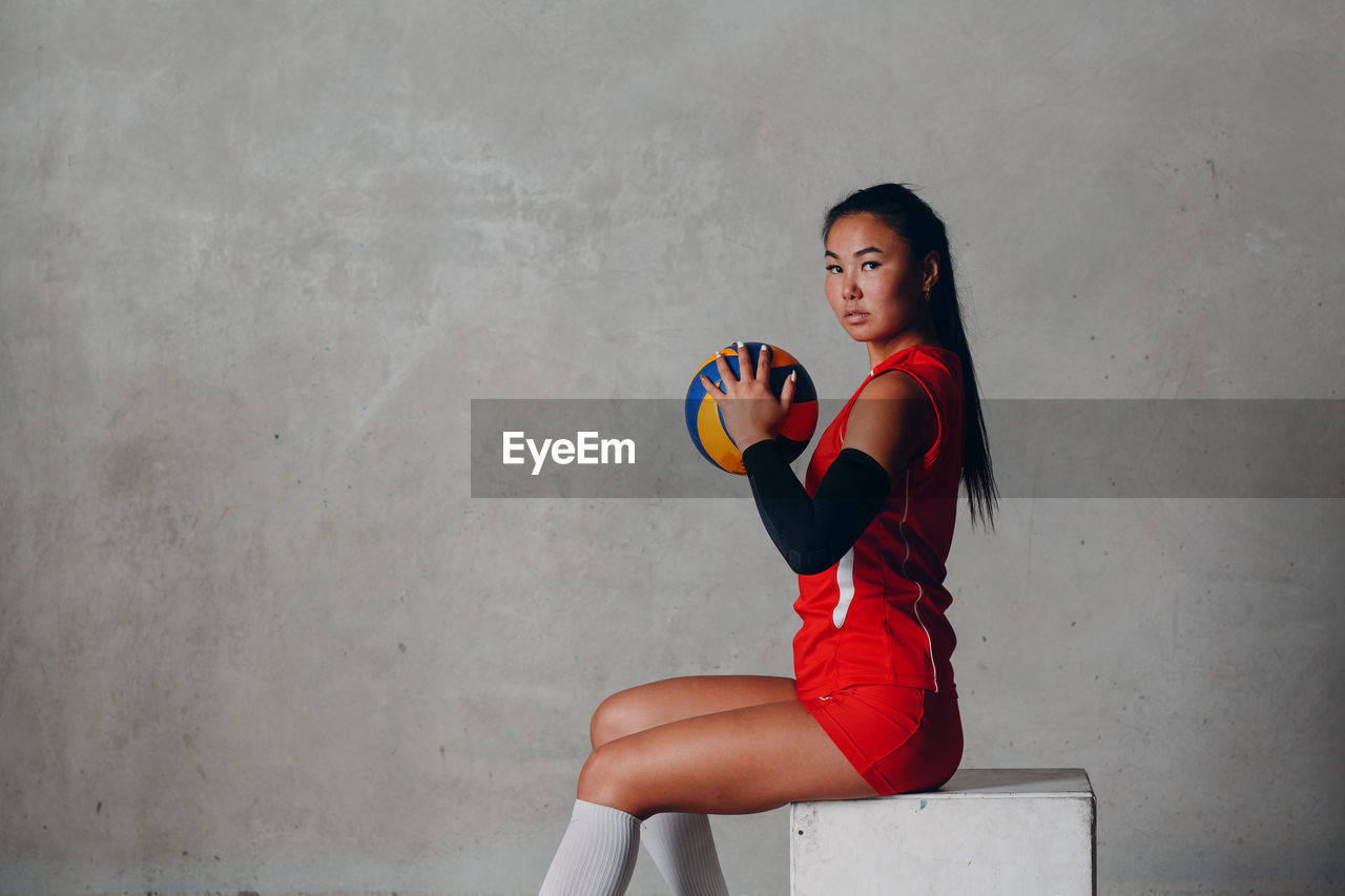 Portrait of young woman against wall