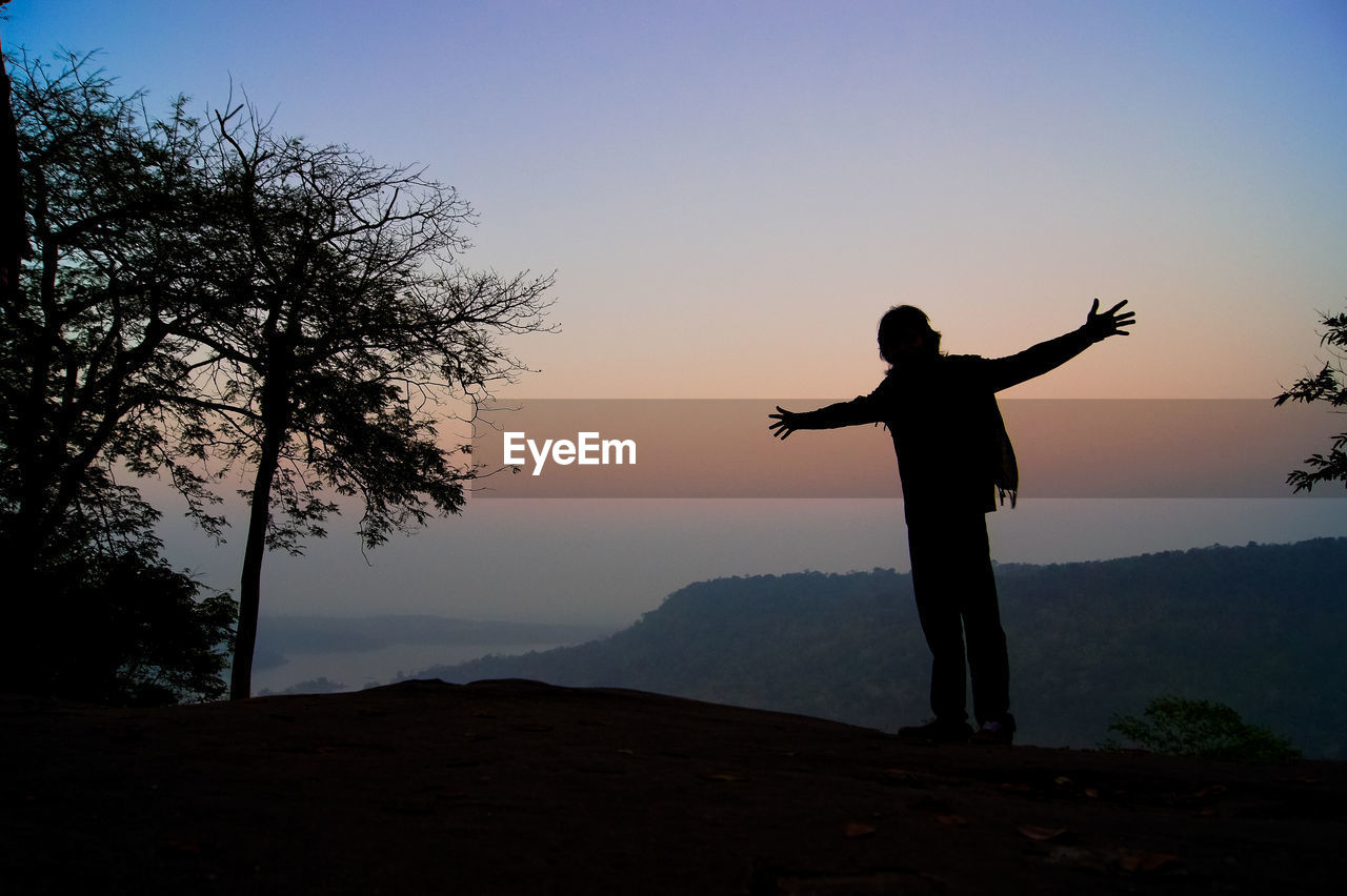 Silhouette man standing on mountain against clear sky