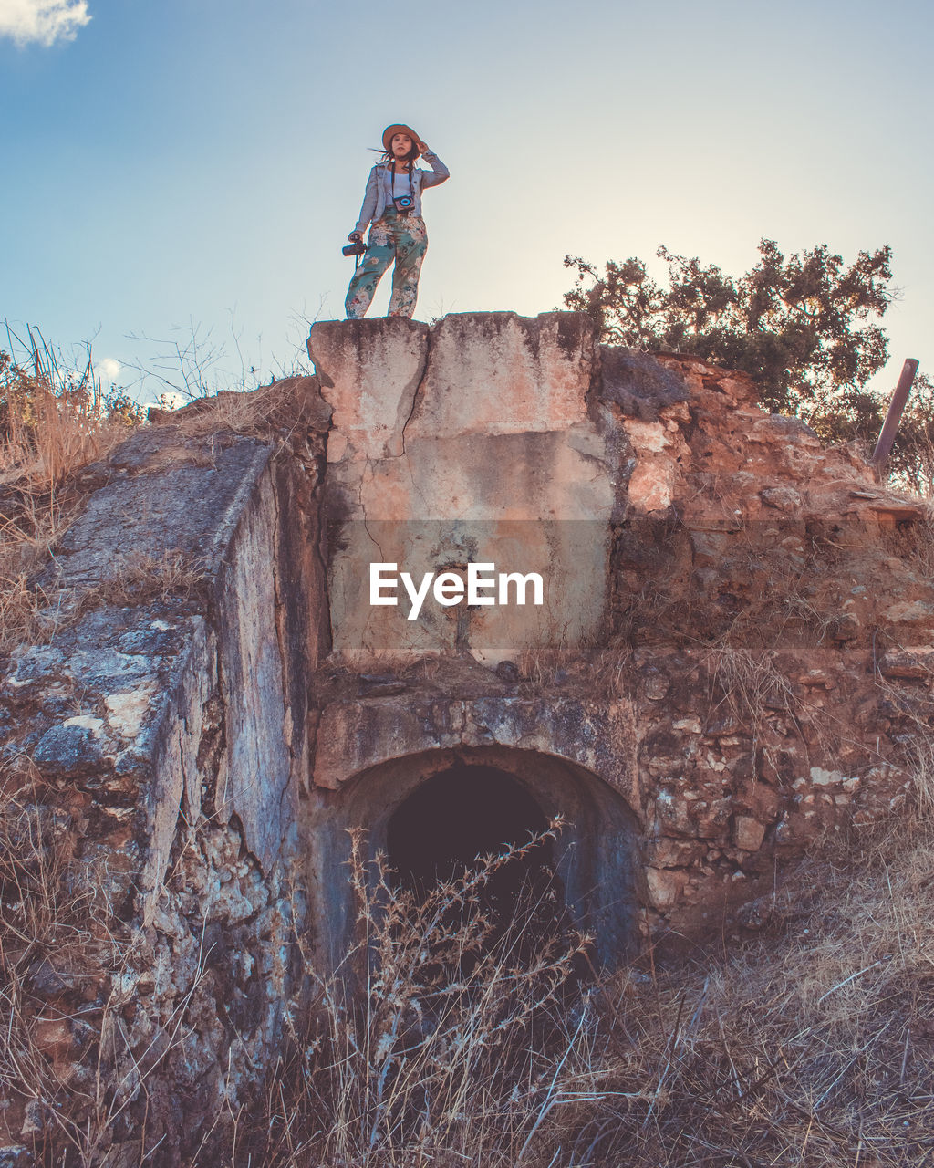 Low angle view of woman standing on abandoned built structure against sky