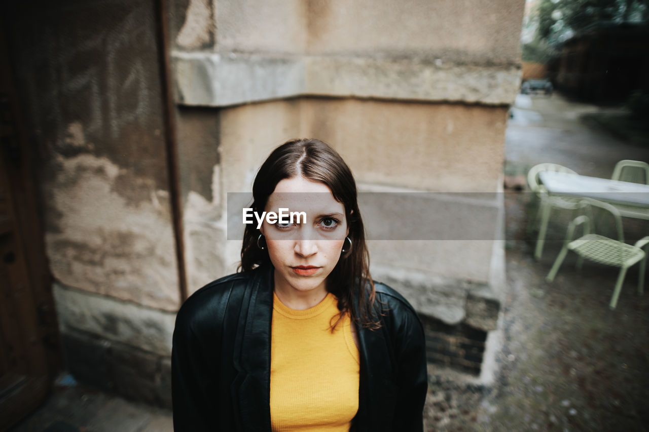 Portrait of young woman standing against wall