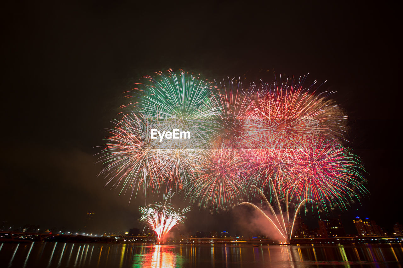 Low angle view of fireworks over lake at night