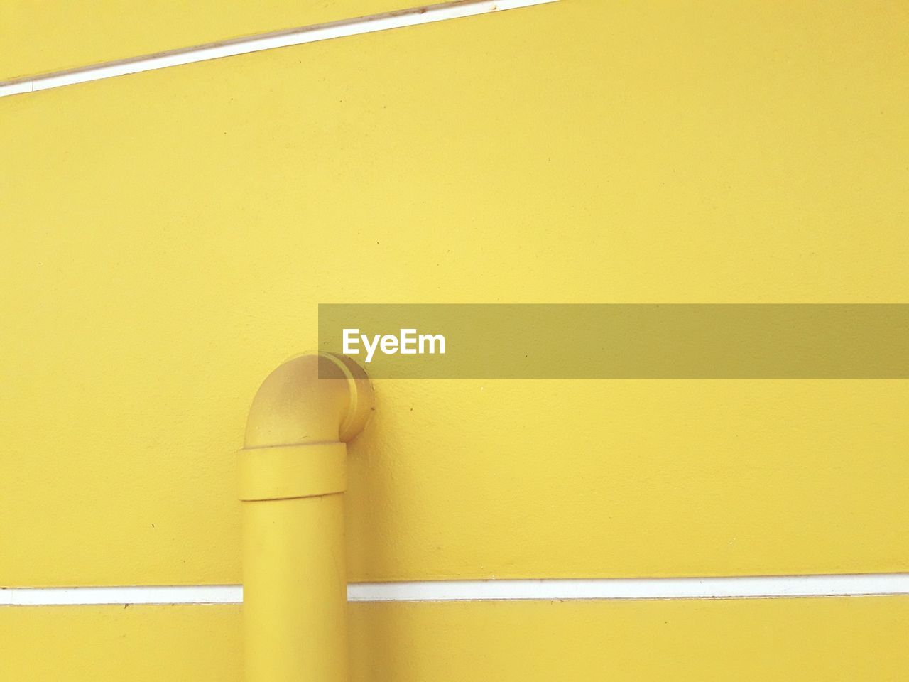 CLOSE-UP OF YELLOW PIPE ON METAL WALL