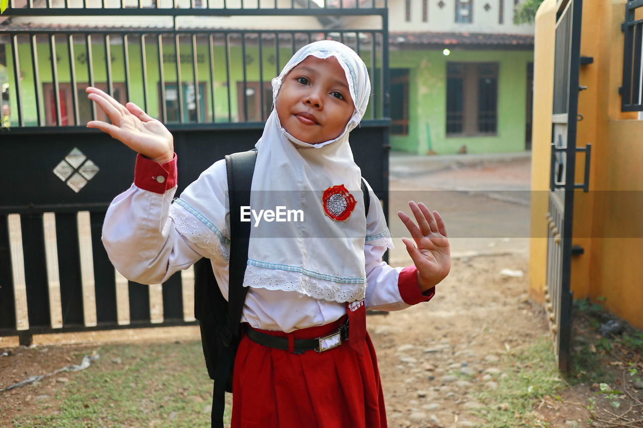 Portrait of girl in hijab standing against gate