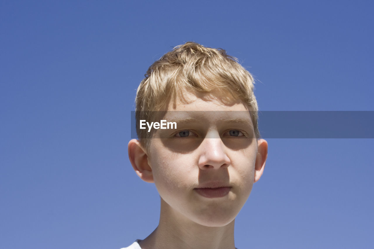 Portrait of teenage boy against clear blue sky