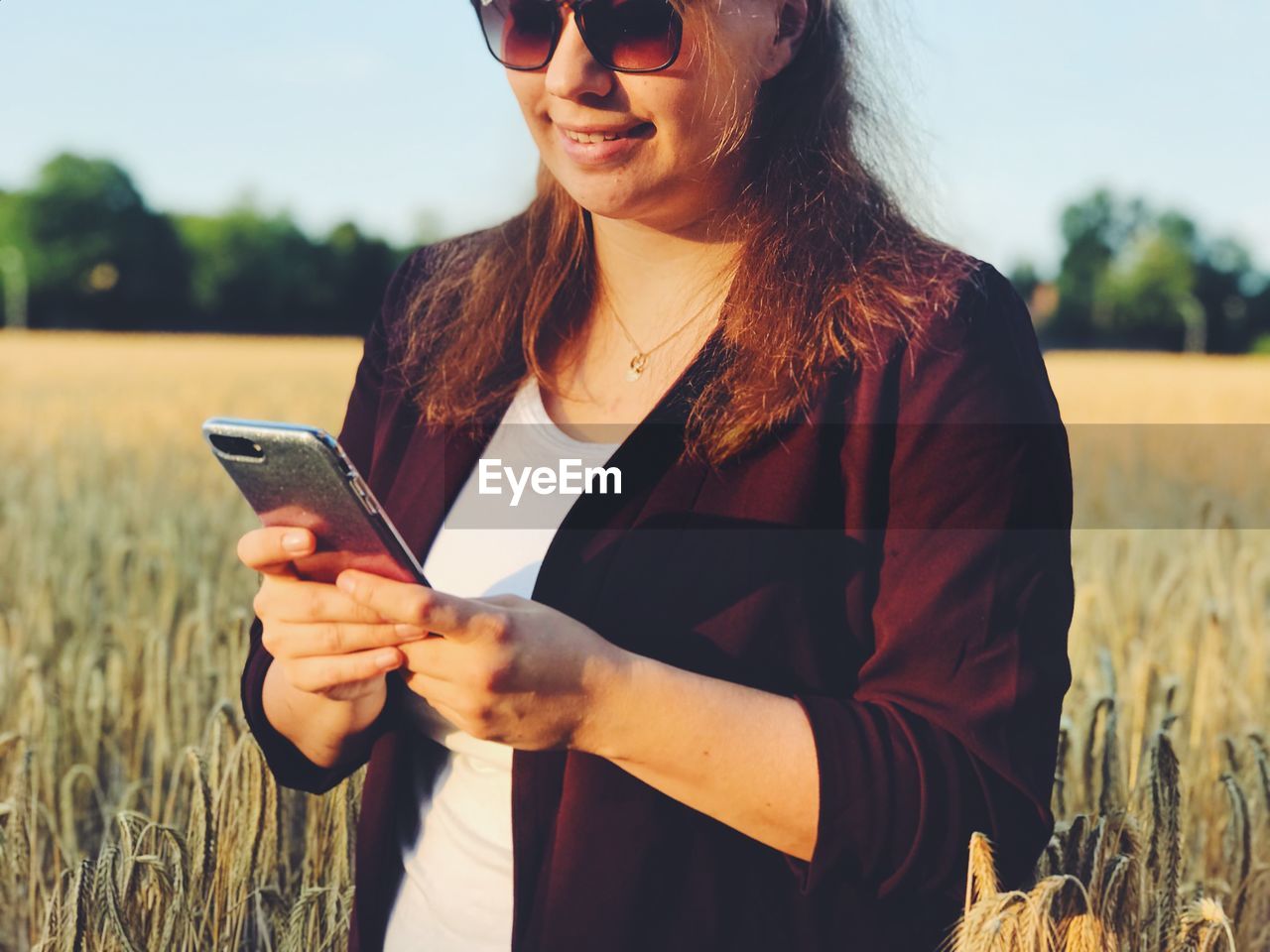 Woman using mobile phone while standing on field