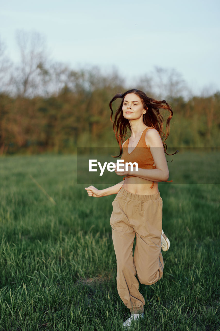 portrait of smiling young woman standing on grassy field