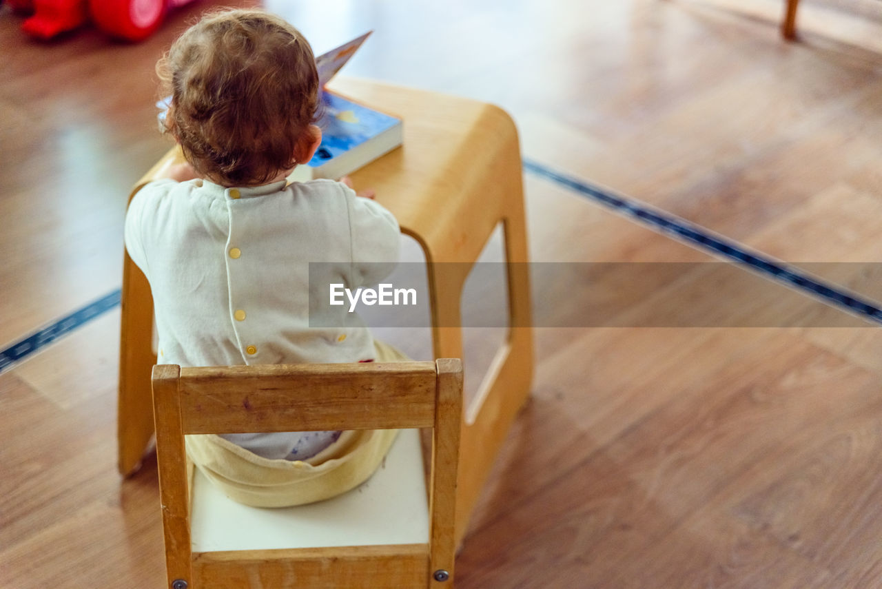 Rear view of boy sitting on table at home