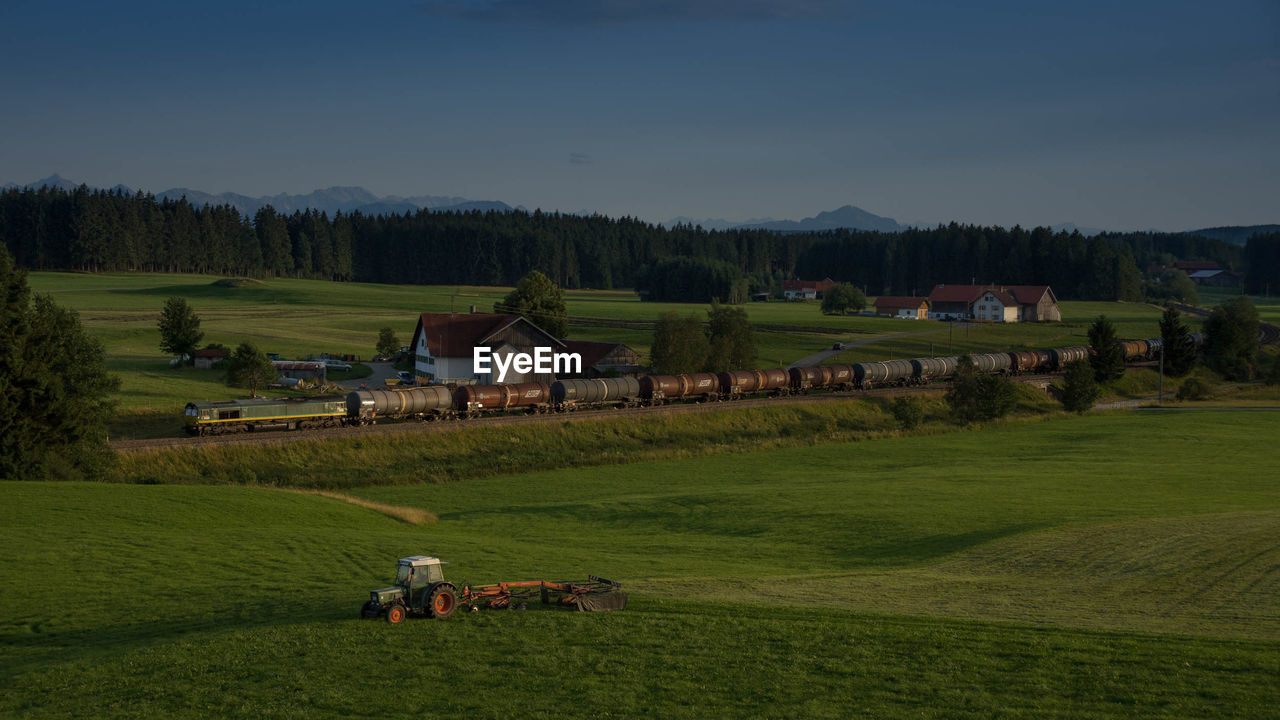 Train amidst grassy landscape against sky