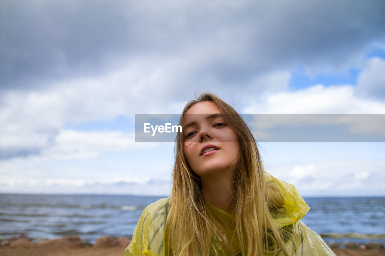 Portrait of smiling young woman against sea at beach