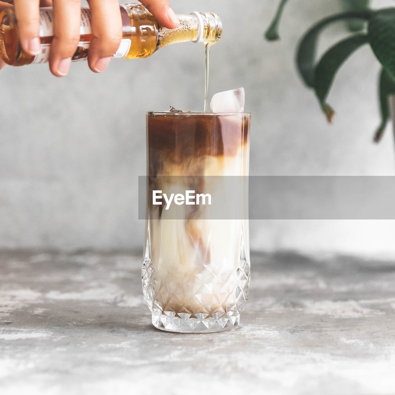 Midsection of person pouring syrup into coffee in glass
