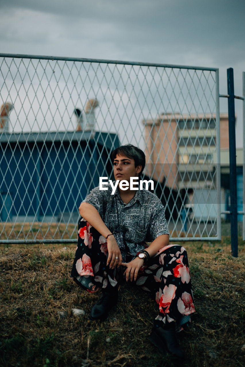 Full length of boy sitting by fence