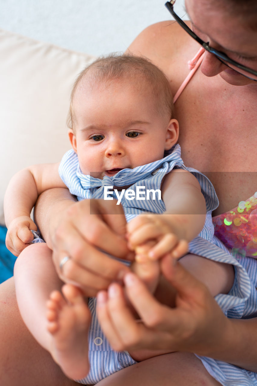 Young mother in bikini holds little infant girl on lap. lifestyle concept.