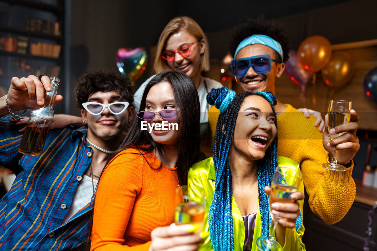 portrait of smiling friends wearing sunglasses while standing in party