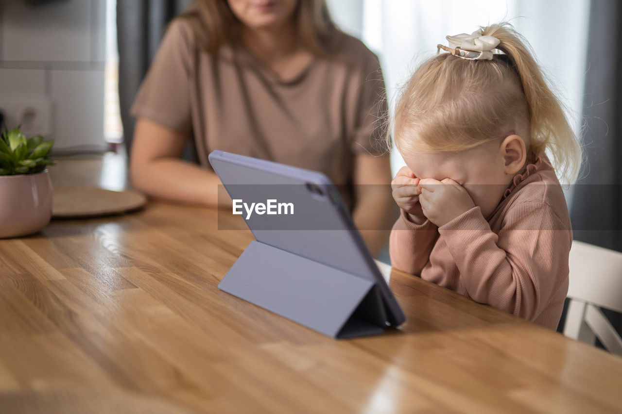 young woman using digital tablet while sitting on table in office