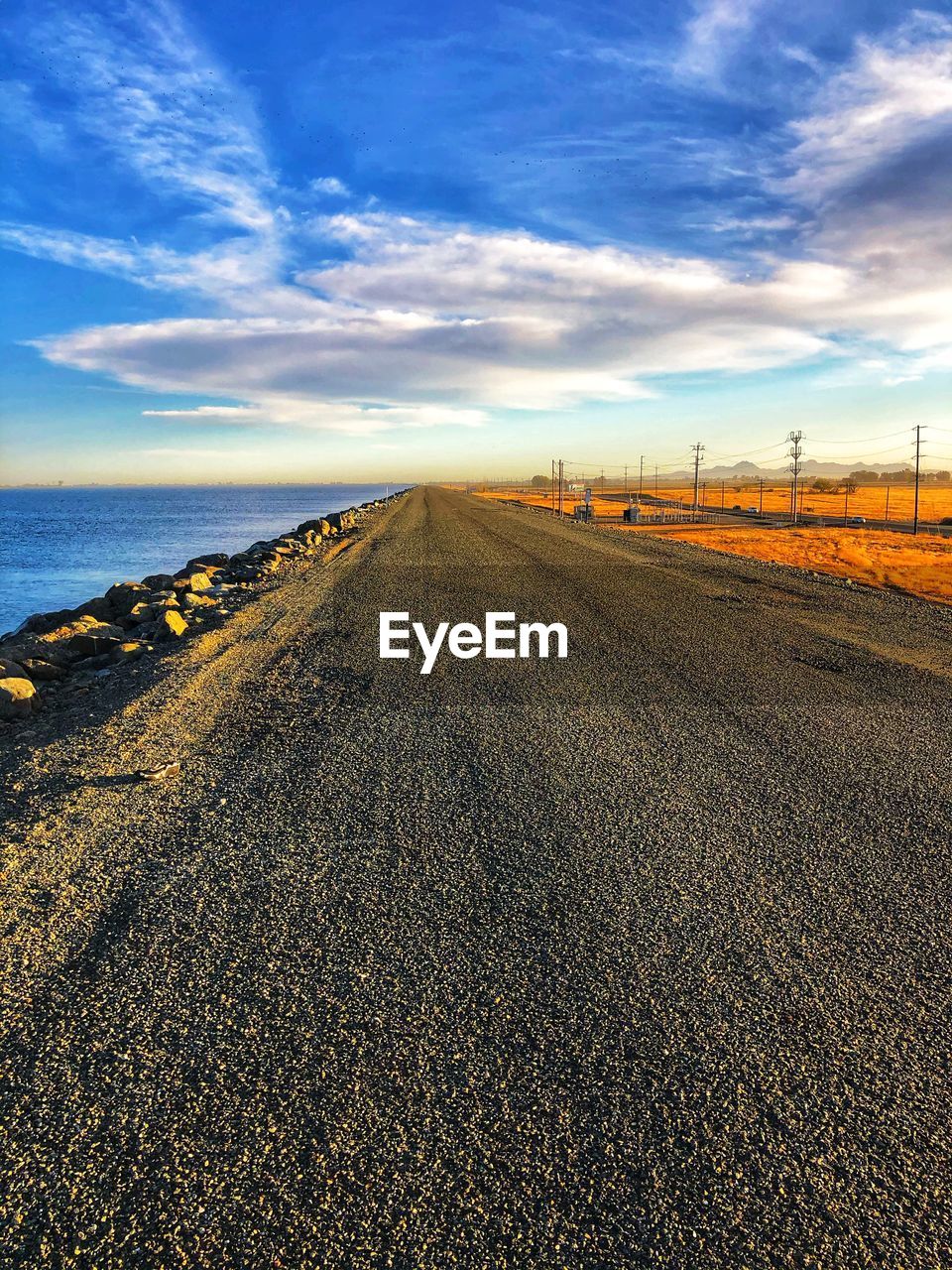 horizon, sky, sea, land, coast, cloud, sand, nature, transportation, sunlight, environment, shore, road, landscape, scenics - nature, field, morning, dusk, ocean, sunrise, beauty in nature, water, no people, beach, natural environment, the way forward, diminishing perspective, tranquility, travel, vanishing point, outdoors, blue, tranquil scene, non-urban scene, urban skyline, wave, asphalt, travel destinations, day