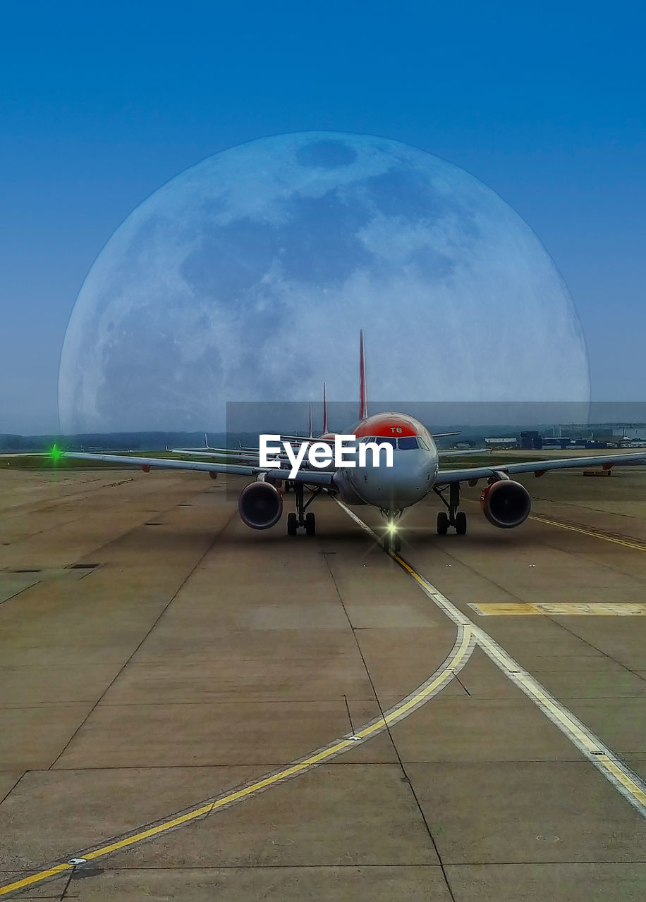 Aircraft waiting to depart at london gatwick airport with a full moon