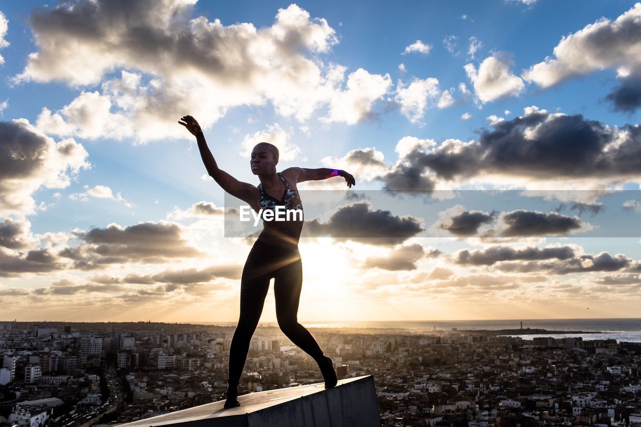 Silhouette of woman standing against sky at sunset