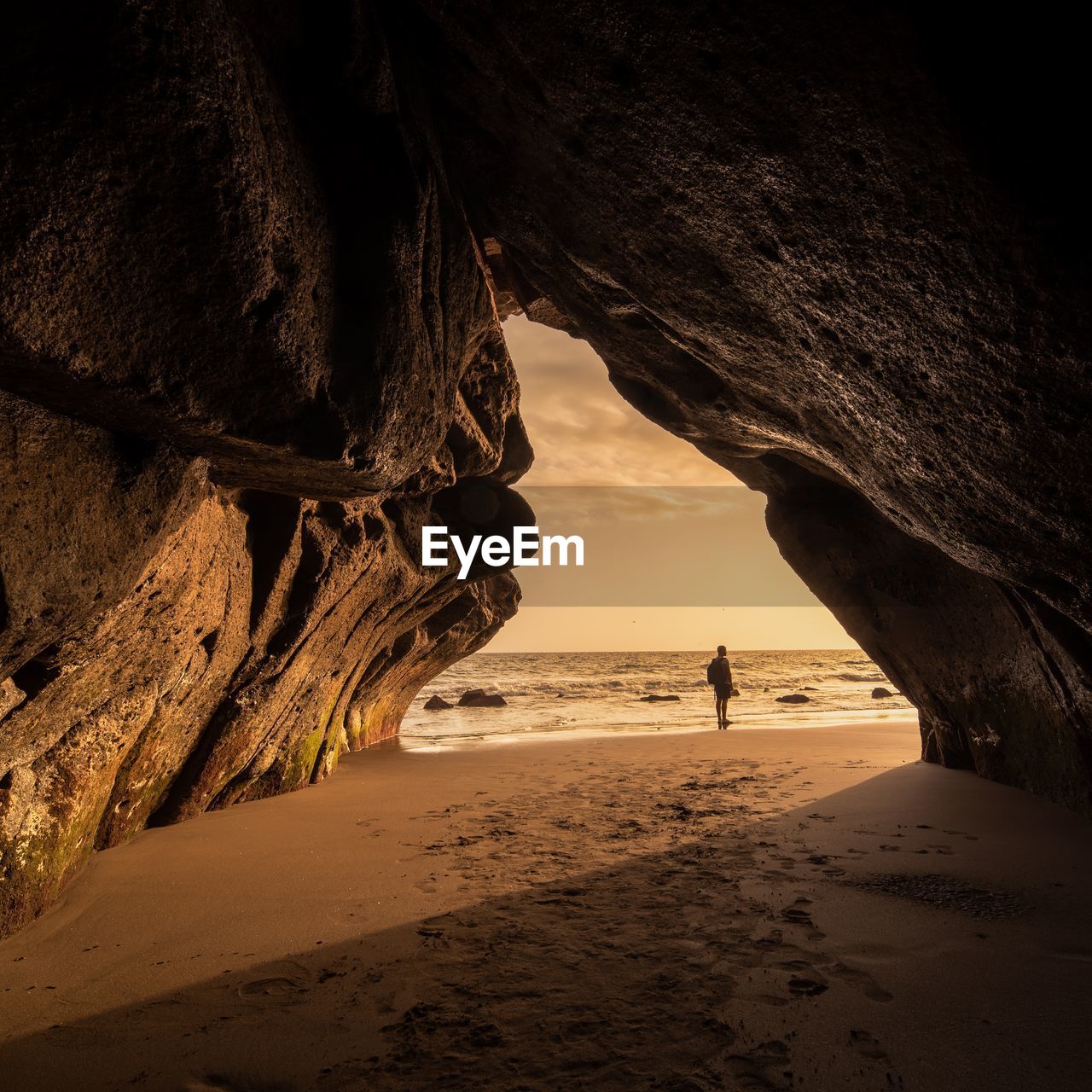 Man walking in cave at beach