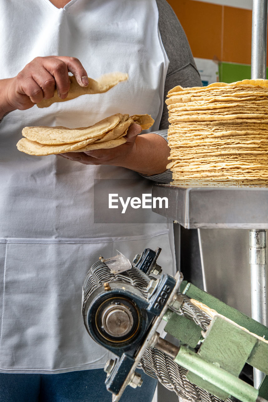 MIDSECTION OF PERSON PREPARING FOOD ON TABLE