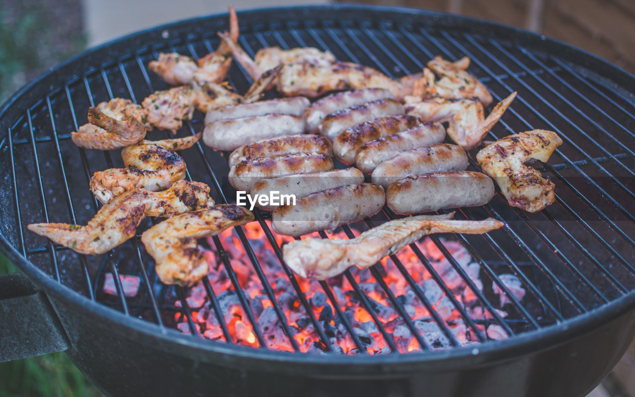 Close-up of chicken wings and sausages on barbecue grill