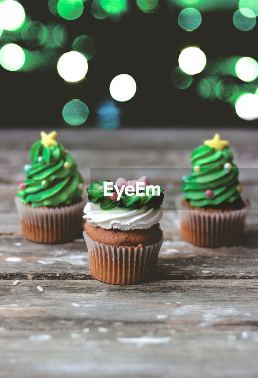 Vanilla cupcakes with christmas decoration, on dark background with colorful christmas lights