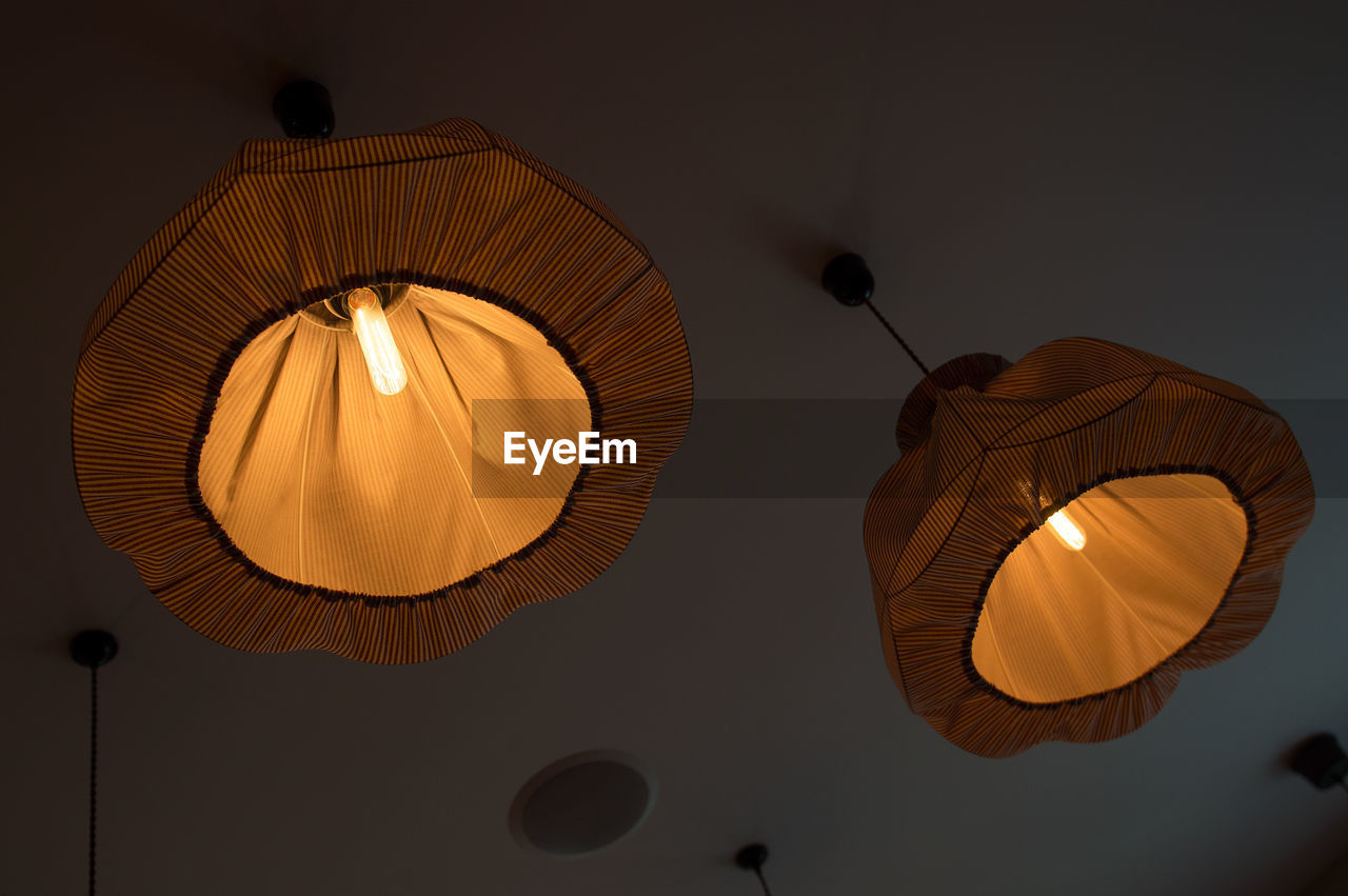 Low angle view of illuminated pendant lights hanging on ceiling