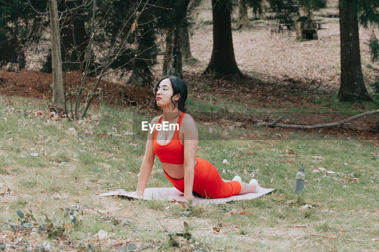 young woman sitting on field in park