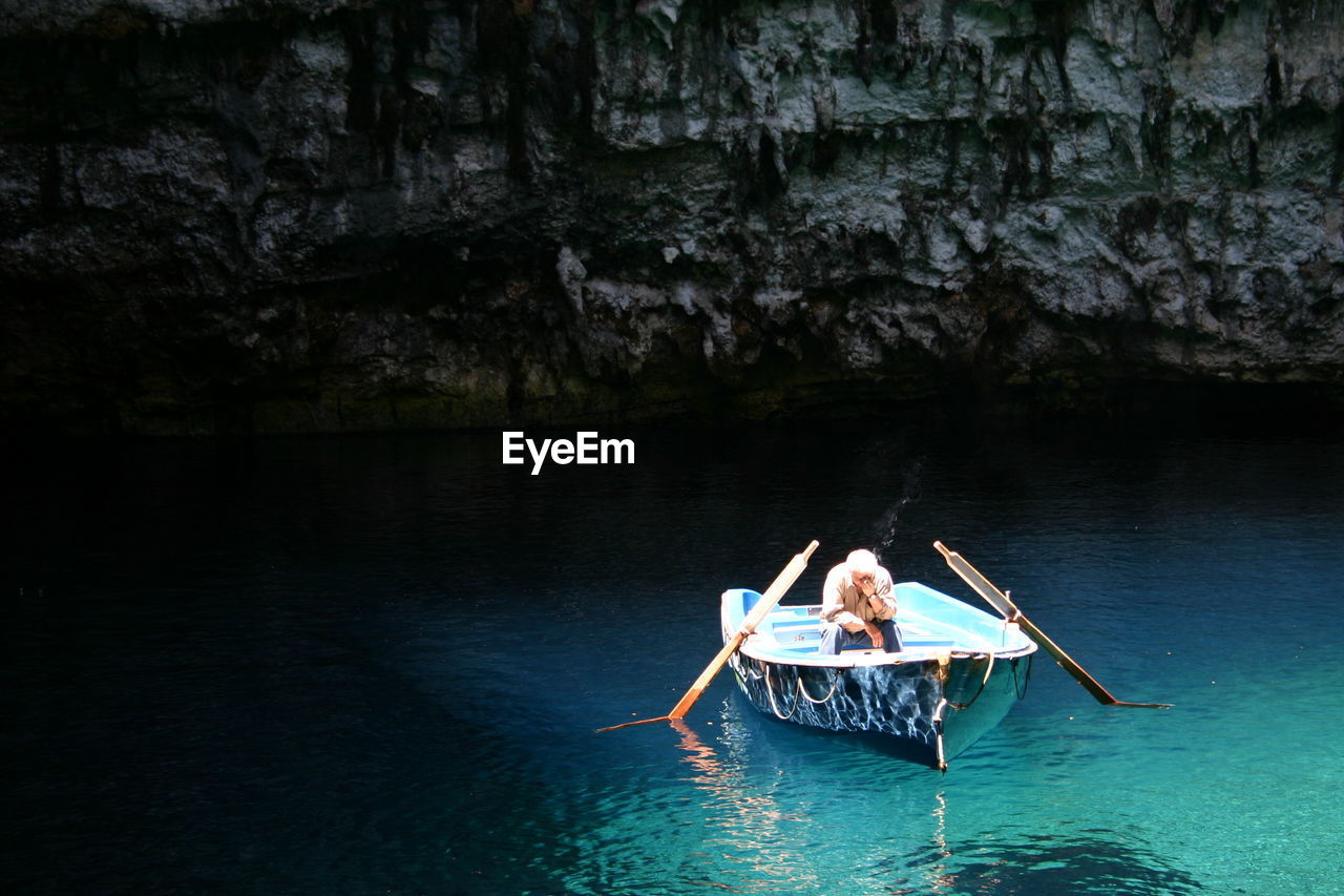 Man sitting in moored boat on lake