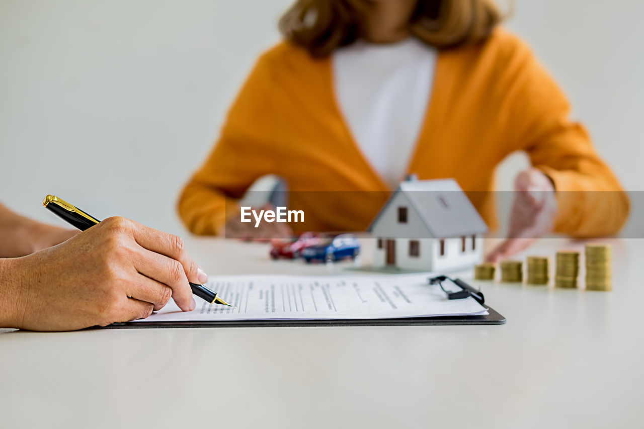 Midsection of businesswoman holding paper while sitting on table