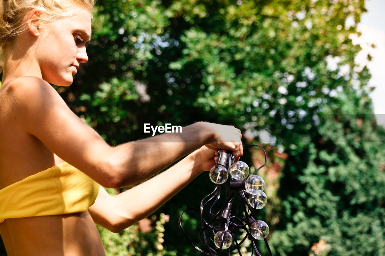 Woman wearing bikini while holding string light