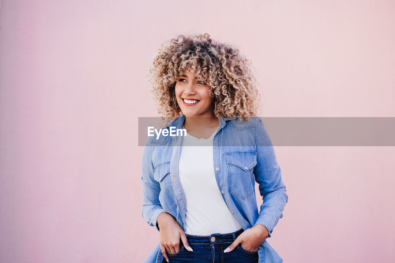 Portrait of smiling hispanic woman with afro hair in city during spring. urban lifestyle